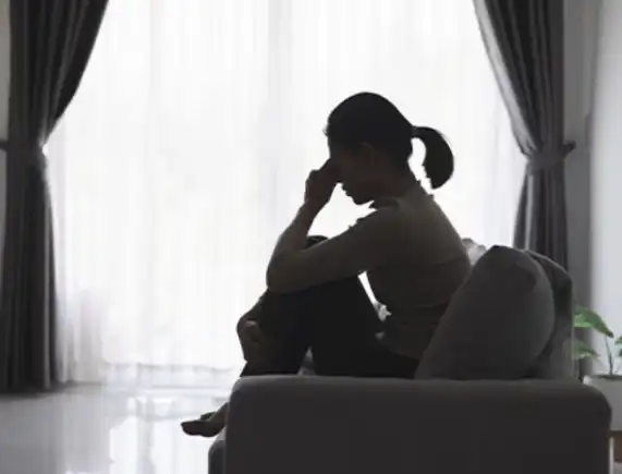 Woman sitting alone, looking distant and withdrawn