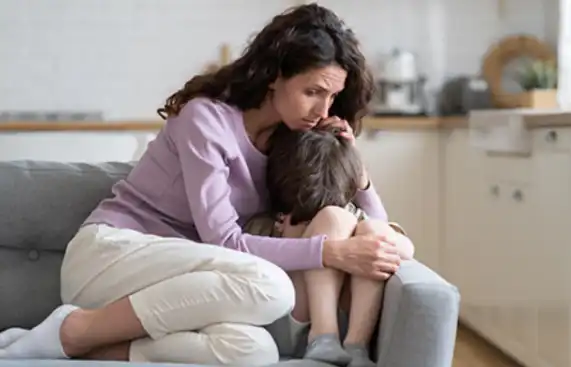 Woman looking exhausted and overwhelmed, comforting a child